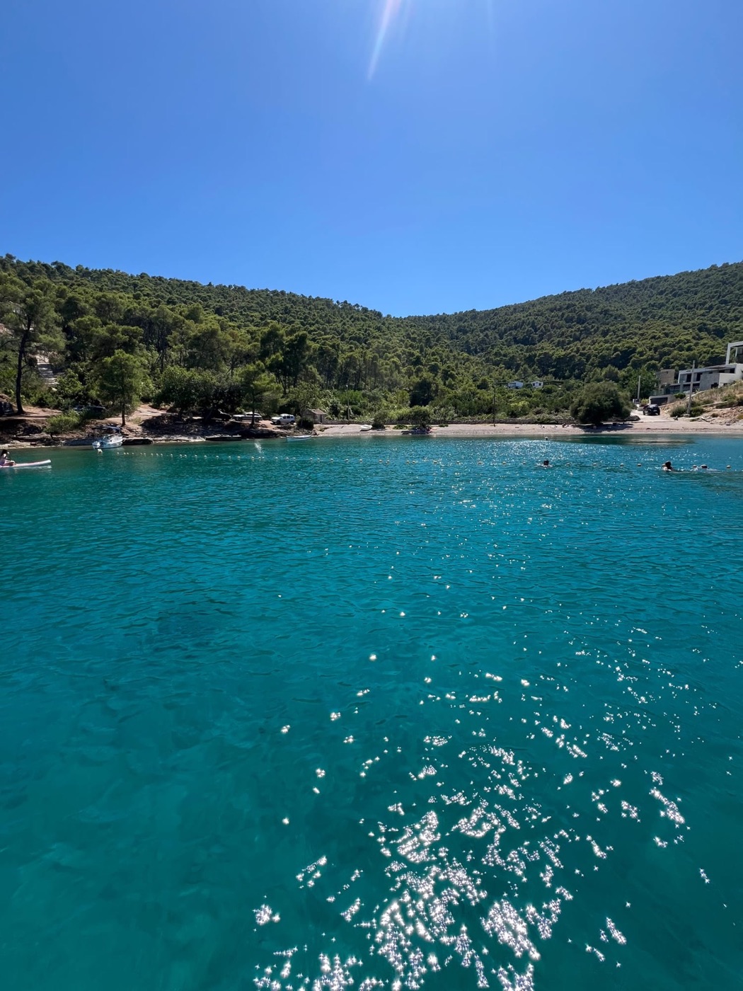 Paddleboard and swimmers in a turquoise Dalmatian bay