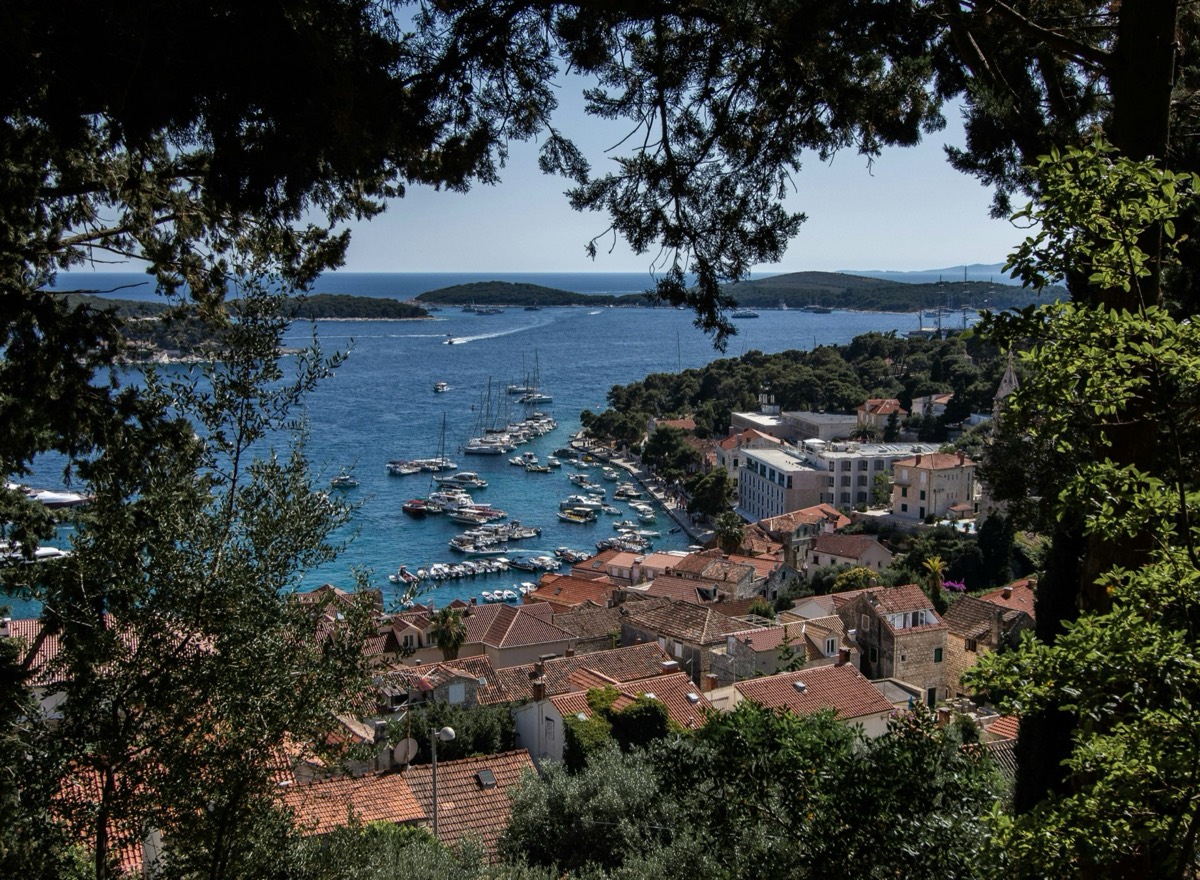 Hvar Town harbor on the Adriatic at sunset with red rooftops and island boats, Croatia